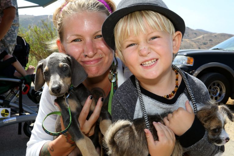 A mother and child joyfully holding puppies at a community dog adoption event